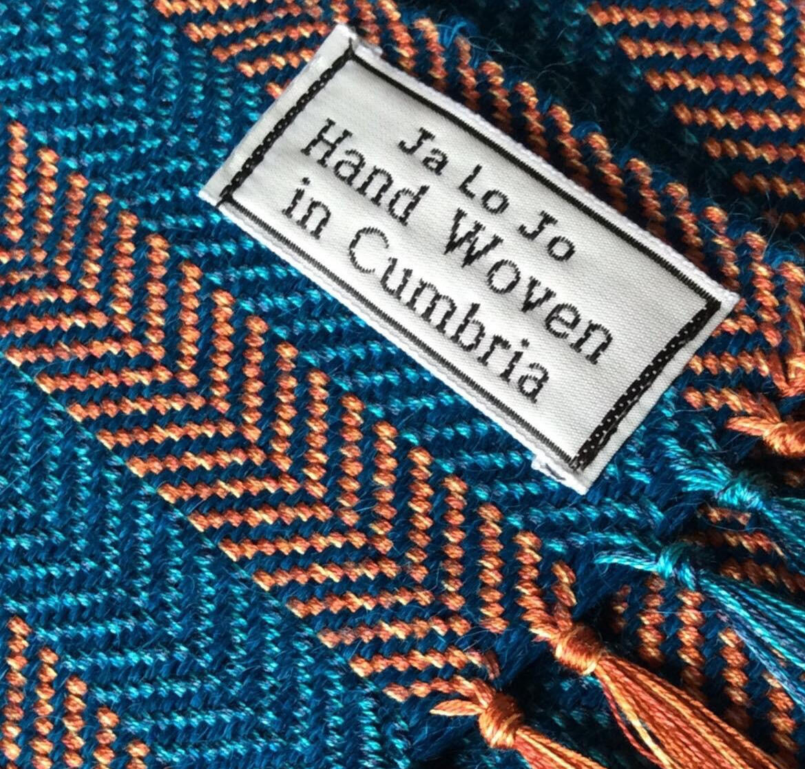 Handwoven orange and blue scarf with JaLoJo label – close-up detail of textile craftsmanship