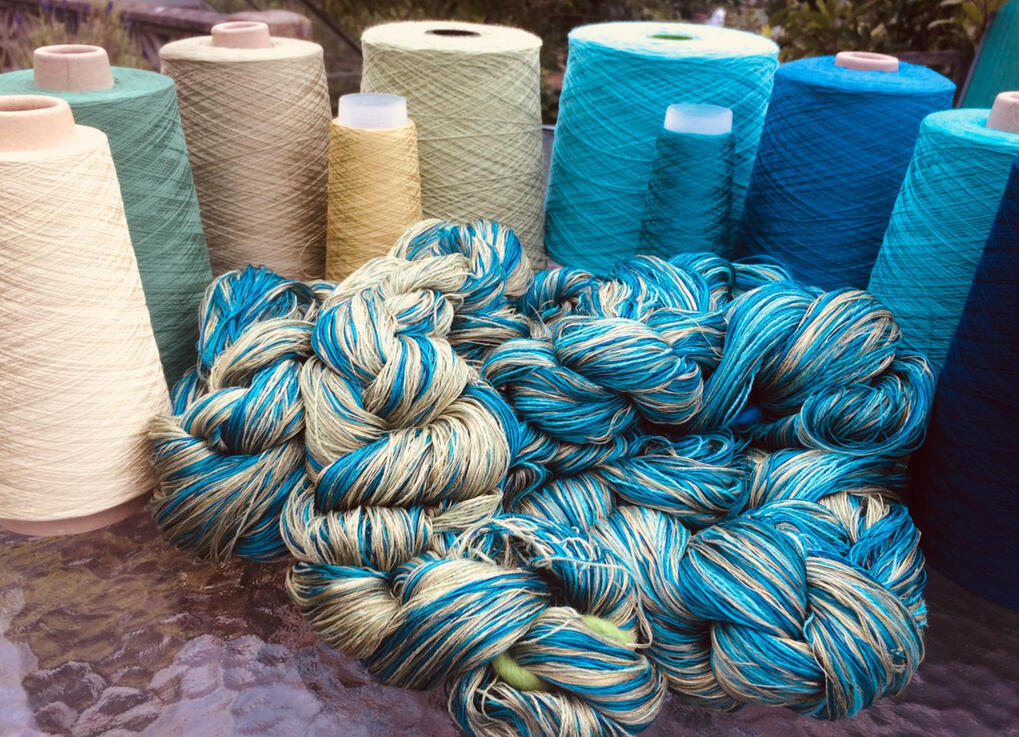 Blue and cream yarn spools with plaited wool in the foreground – natural fibre palette